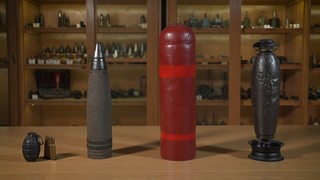 Verschiedene Arten von alten Bomben stehen aufgereiht auf einem Tisch.