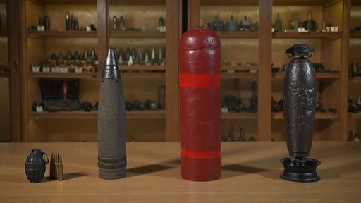 Verschiedene Arten von alten Bomben stehen aufgereiht auf einem Tisch.