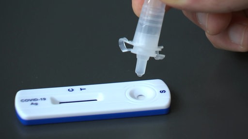 Ein Coronatest wird mit der Flüssigkeitslösung betropft.