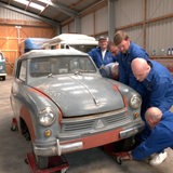 Männer schrauben an einem Oldtimer.