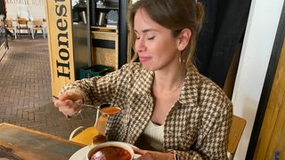 Eine junge Frau genießt Borsch in der Markthalle in Bremen