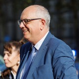 Ein Mann mit Brille und Anzug lächelt.