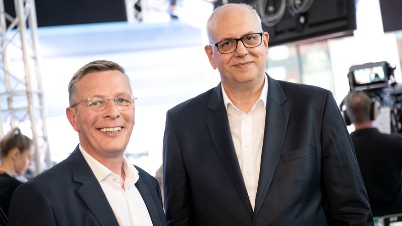 Andreas Bovenschulte und Frank Imhoff stehen gut gelaunt nebeneinander und gucken ins Bild