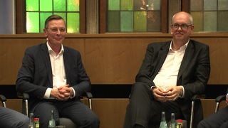 Spitzenkandidaten von CDU und SPD, Frank Imhoff und Andreas Bovenschulte, sitzen bei einer Veranstaltung und beantworten Fragen.