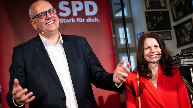 Andreas Bovenschulte, Spitzenkandidat der SPD in Bremen, und seine Partnerin Kerstin Krüger stehen nach Bekanntgabe der ersten Prognose für die Wahl zur Bremischen Bürgerschaft auf der Bühne der SPD-Wahlparty.