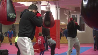 Ein Boxer steht in Kampfhaltung an einem Boxsack und trainiert.