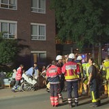 Feuerwehrkräfte und Altenheimbewohner stehen auf einer Straße.