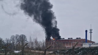 Qualm und Flammen dringen aus einem Backsteingebäude