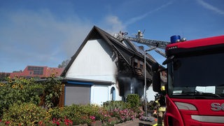 Ein brennendes Haus wird von der Feuerwehr gelöscht.