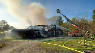 Eine Scheune brennt, Feuerwehrleute löschen das Feuer.