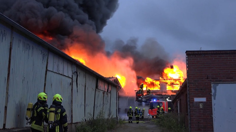 Feuerwehrleute löschen Brand in Fabrik, Flammen und Rauch an Gebäude