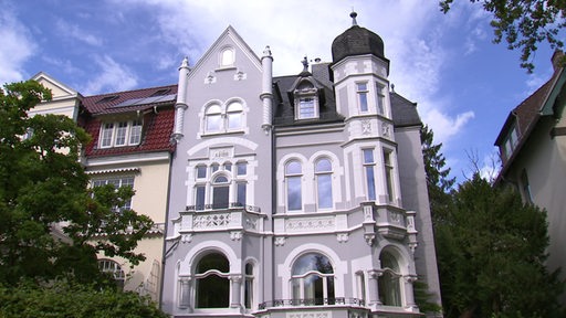 Blick auf eine grau gestrichene Villa.