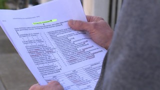 Eine List mit dem Titel "Schlechte Adressen!!" auf einem Blatt Papier, das von einem Mann in den Händen gehalten wird.
