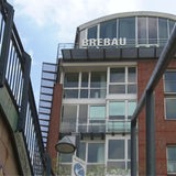 Eine Treppe ist aus der Froschperspektive zu sehen. Dahinter ragt das Gebäude der Brebau in den Himmel.