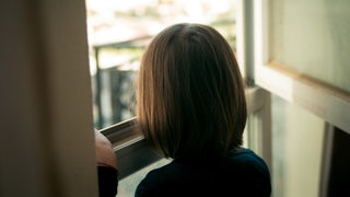 Ein Mädchen schaut aus dem Fenster.