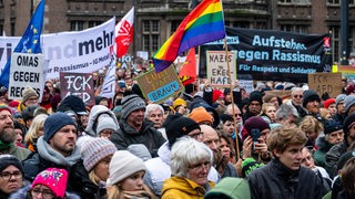 Menschen demonstrieren auf dem Bremer Marktplatz. Dabei sind auf Plakaten Aufschriften wie "FCK AfD", "Omas gegen Rechts" und "Aufstehen gegen Rassismus"