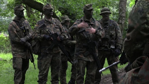 Mehrere Soldaten in Tarnmaskierung im Wald