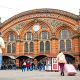 Reisende mit Koffern laufen zum Bremer Hauptbahnhof. 