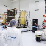 Mehrere OHB-Mitarbeiter begutachten einen Wettersatelliten.