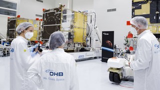 Mehrere OHB-Mitarbeiter begutachten einen Wettersatelliten.