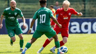 Ein Spieler des FC Oberneuland dribbelt mit dem Ball vor seinen Gegenspielern.