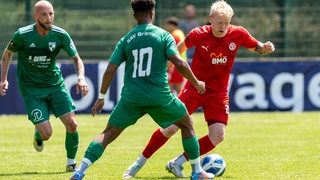 Ein Spieler des FC Oberneuland dribbelt mit dem Ball vor seinen Gegenspielern.