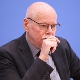 Ulrich Mäurer sitzt auf dem Podium und schaut konzentriert.