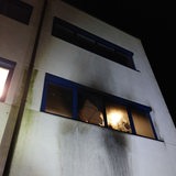 Das eingeschlagene Fenster eines Bürogebäudes voller Ruß 
