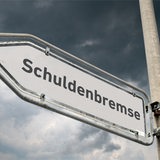 Schild mit Schuldenbremse vor dunklen Wolken