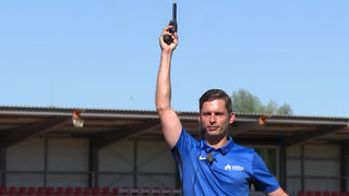 Starter Kim Jokel reckt die Pistole hoch in die Luft, bevor er den Lauf im Stadion in Arsten anschießt.