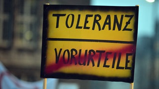Auf einem Schild steht oben das Wort "Toleranz", darunter das durchgetrichene Wort "Vorurteile"