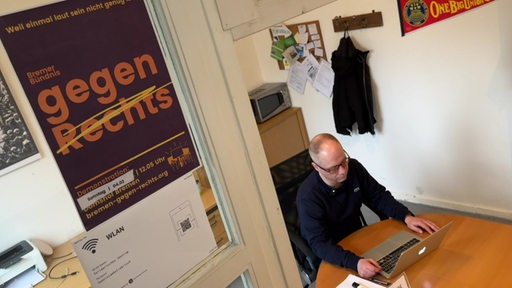 Der Organisator des Bremer Bündnis gegen Rechts Tobias Helfst sitzt mit einem Laptop am Tisch. 