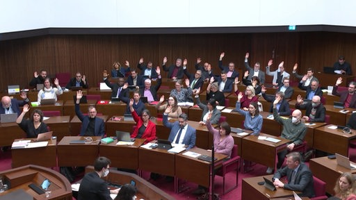 Mitglieder der Bremischen Bürgerschaft heben während einer Abstimmung zum Nachtragshaushalt die Hände.