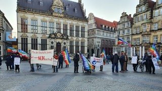 Eine Gruppe Menschen steht auf dem Bremer Marktplatz und protestiert für Frieden