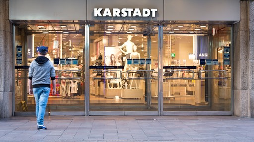 Der Eingang der Bremer Karstadt-Filiale. Im Vordergrund läuft ein junger Mann. Über der Tür steht "Karstadt".