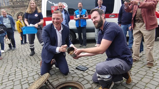 Frank Imhoff und Pascal Paulat vom DRK Bremen holen Spendengeld aus dem Bremer Loch