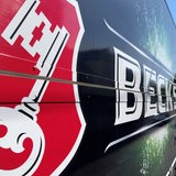 Seitenansicht eines LKW der Firma "Beck's" mit dem einem Schlüssel im Vordergrund.