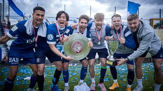 Spieler des Bremer SV bejubeln den Gewinn des Pokals und der Meisterschaft.