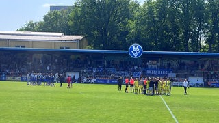 Spieler des Bremer SV und des FC Teutonia Ottensen stehen getrennt voneinander auf dem Platz am Bremer Panzenberg.