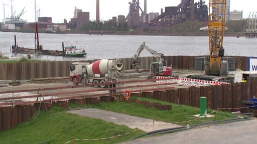 Mehrere Baufahrzeuge sind im Einsatz am Ufer der Weser