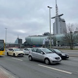 Bus und Pkw fahren auf einer Straße, im Hintergrund das Klimahaus und das Atlantic-Hotel.