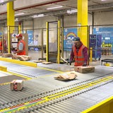 Im Bremerhavener Amazon-Verteilzentrum arbeiten drei Männer an einem Fließband.