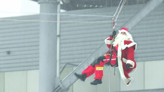 Eine Person im Nikolaus-Kostüm hängt in den Seilen.
