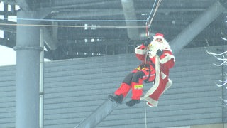 Ein als Nikolaus verkleideter Mann hängt an einem Seil.