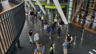 Mehrere Personen stehen in einer Halle vor einem Eingang.