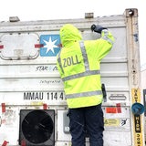 Mehrere Zoll-Mitarbeitende an einem Container