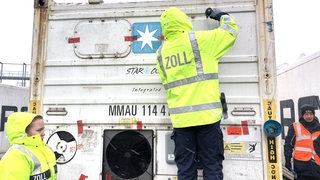 Mehrere Zoll-Mitarbeitende an einem Container