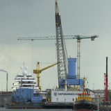 Ein Kran ragt neben einem Schiff in den Himmel.