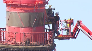 Ein Mann steht auf einem Kran und arbeitet an der Kuppel des Molenturms in Bremerhaven.