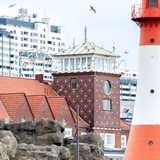 Möwen fliegen bei trübem Wetter über dem Zoo am Meer und der Strandhalle. Im Hintergrund ist das Columbus Center zu erkennen. 